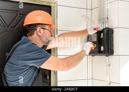 L'électricien est l'installation d'un compteur électrique sur le mur. Banque D'Images