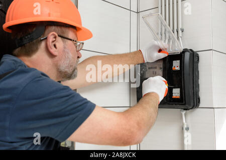 L'électricien est l'installation d'un compteur électrique sur le mur. Banque D'Images