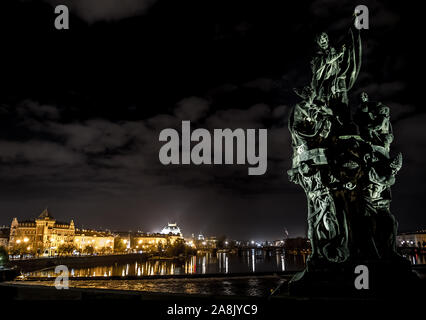 Statue sur le Pont Charles et la vue sur la rivière Moldova et bâtiments illuminés à Prague en République Tchèque Banque D'Images