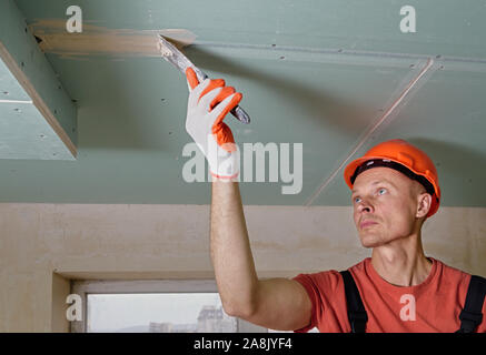 Le travailleur est le remplissage des joints de plâtre, le gypse putty. Banque D'Images