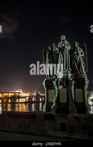 Statue sur le Pont Charles et la vue sur la rivière Moldova et bâtiments illuminés à Prague en République Tchèque Banque D'Images