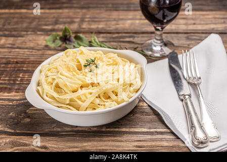 Des pâtes à la sauce béchamel dans une assiette blanche en bois rustique, de fond de table, lumière douce - style de cuisine italienne Banque D'Images