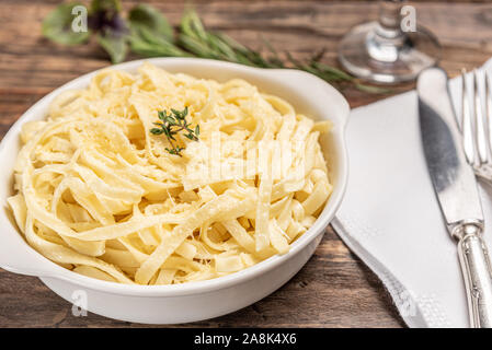 Des pâtes à la sauce béchamel dans une assiette blanche en bois rustique, de fond de table, lumière douce - style de cuisine italienne Banque D'Images