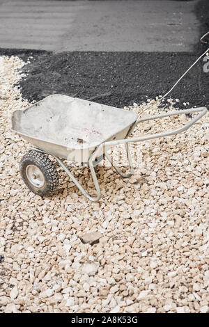 Brouette de construction. Pose de l'asphalte, couvrant la fosse, sur les décombres. Compacteurs d'asphalte est l'exécution de travaux de réparation des routes. Banque D'Images