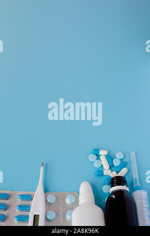 Traitement du rhume et de la grippe. Divers médicaments, un thermomètre, une pulvérisation d'une congestion nasale et une douleur dans une gorge sur un fond bleu. Copier l'espace. Medic Banque D'Images