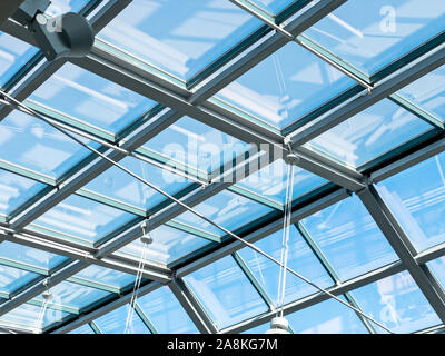 Libre vue de l'intérieur du toit en verre transparent moderne. bleu ciel à travers un plafond de verre Banque D'Images