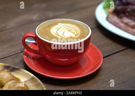Télévision avec café blanc motif coeur dans une tasse rouge et par t de croissant et bacon salade par le côté. Breakfast set concept. Banque D'Images
