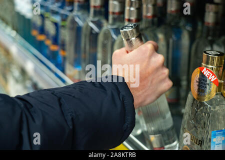 Yekaterinburg, Russie - Novembre 2019. Prenez une bouteille de vodka à une étagère dans le marché. Main d'un homme dans une veste chaude. Une bouteille de marque Khortytsa Banque D'Images