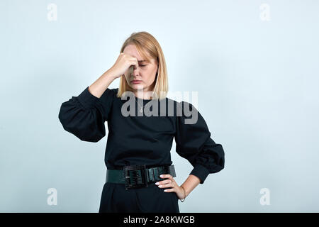 Assez jeune femme ikeeping les yeux fermés et la main mise sur le nez sur le mur isolé Banque D'Images