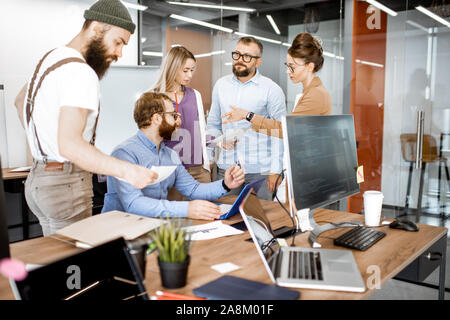 Divers Groupe de collègues qui travaillent dans les bureaux modernes, having discussion ou petite conférence sur un lieu de travail avec des ordinateurs Banque D'Images