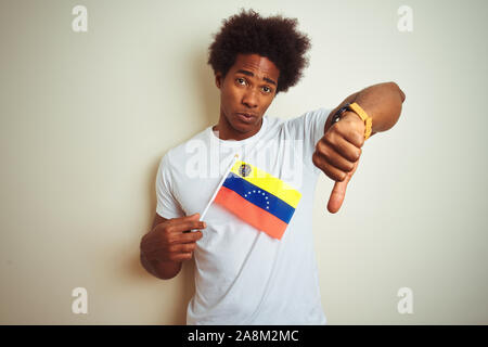 South American man holding Venezuela drapeau vénézuélien debout sur fond blanc isolé, visage en colère avec signe négatif montrant non avec les pouces Banque D'Images