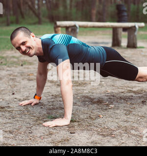 Athletic man smiling tout en faisant l'extérieur pushups Banque D'Images