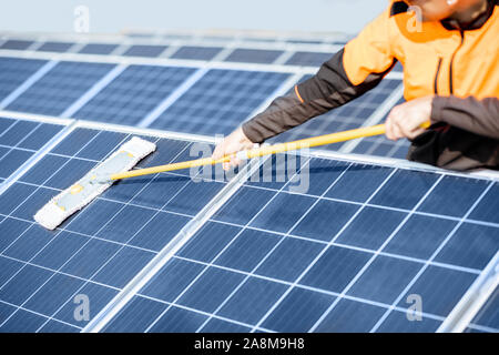 Nettoyeur professionnel en vêtements de protection nettoyage de panneaux solaires avec un mob. Concept de service de nettoyage de l'usine d'énergie solaire Banque D'Images