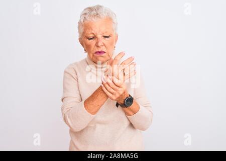 Aux cheveux gris Senior woman wearing sweater col roulé debout sur fond blanc isolées souffrant de douleur sur les mains et les doigts, l'arthrite inflammatio Banque D'Images