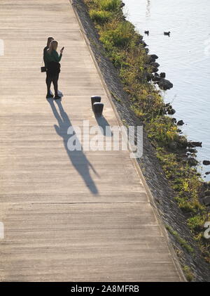 Les jeunes femmes sur la promenade Riverside sur une journée ensoleillée d'automne Banque D'Images