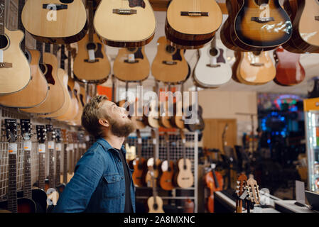 Jeune mec choix guitare acoustique dans music store Banque D'Images