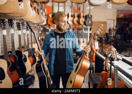 Jeune mec choix guitare acoustique dans music store Banque D'Images