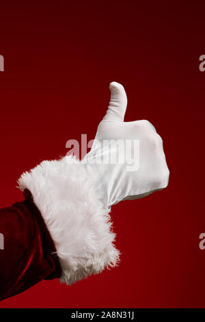 Close up of Santa Claus part showing Thumbs up against red background Banque D'Images