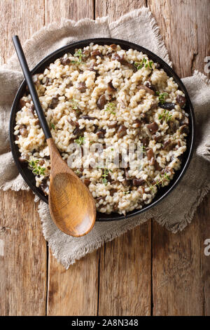 L'italien (Orzotto perlotto) aux cèpes et le thym libre sur une plaque sur la table. Haut Vertical Vue de dessus Banque D'Images