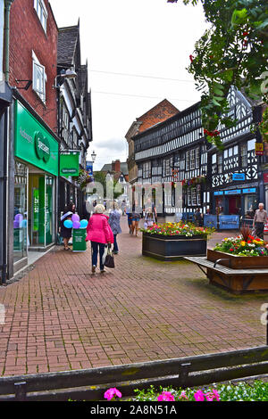 Vue de l'ancienne à colombages dans la rue principale de Nantwich avec le 16ème siècle Le Crown Inn au centre de la distance. Shoppers passant. Banque D'Images