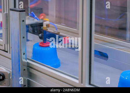 Casseroles sur la courroie du convoyeur de machine de moulage par injection en plastique avec bras robotisé Banque D'Images