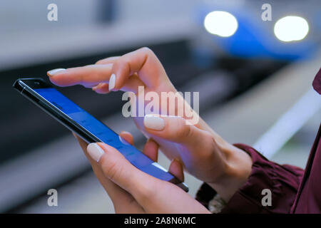 Femme à l'aide du smartphone sur le plate-forme du métro Banque D'Images