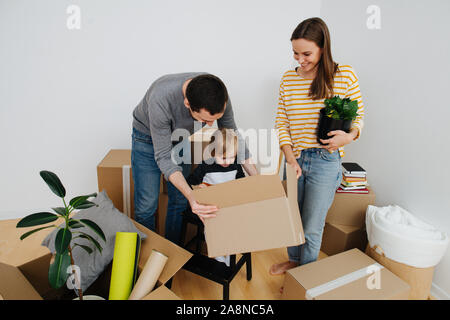 Heureux jeune famille déménagement dans une nouvelle maison, déballage ensemble beaucoup de boîtes de carton Banque D'Images