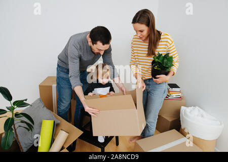 Jeune famille déménagement dans une nouvelle maison, déballage ensemble beaucoup de boîtes de carton Banque D'Images