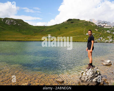 Une jolie brunette d'une vingtaine d'années debout sur un rocher dans un lac de montagne Banque D'Images