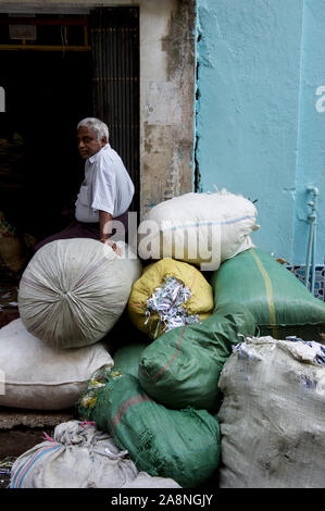 Un homme assis sur des sacs de papier à recycler. Yangon Myanmar Birmanie. Banque D'Images