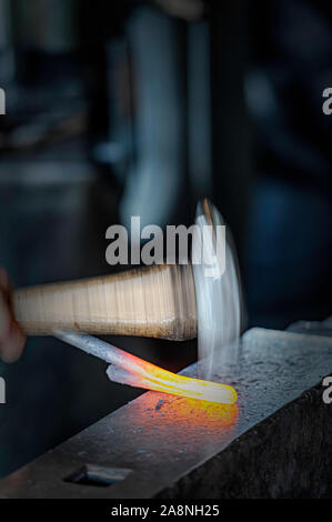 Marteau de forgeron et la formation d'une barre de fer chaud rouge Banque D'Images