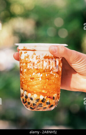 Lait glacé femme hand holding bubble tea avec perles de tapioca et de caramel Banque D'Images