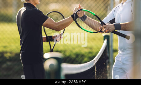 Deux jeune homme se serrer la main après avoir joué au tennis. Les joueurs de tennis se serrer la main sur le net après le match. Banque D'Images