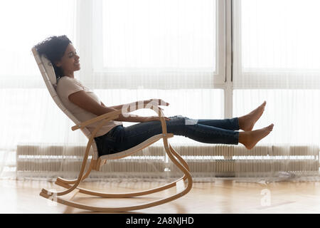 Happy African American Woman relaxing in chair at home confortable Banque D'Images