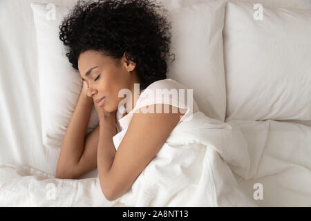 African American Woman with hands sous joue sleeping in bed Banque D'Images