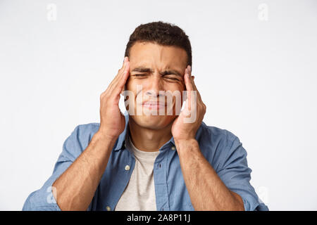 L'homme d'énormes hangover après la célébration du nouvel an, fronçant, grimaces dérangé. Beau gars souffrant des maux de tête, de fermer les yeux, de toucher des temples, ont de mauvais Banque D'Images