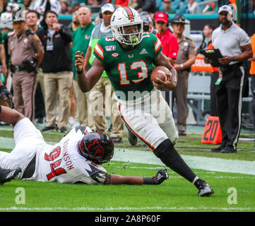 Novembre 09, 2019 Les Championnats de France : d'utiliser de nouveau DeeJay Dallas (13) s'exécute avec la balle passé Louisville Cardinals joueur de ligne défensive G.G. Robinson (94) pour marquer un touchdown contre les Louisville Cardinals lors d'un match de football collégial au Hard Rock Stadium de Miami Gardens, en Floride. Les Hurricanes ont remporté 52-27. Mario Houben/CSM Banque D'Images