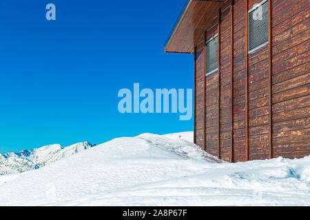 Mur d'une maison en bois dans les montagnes dans la neige. Journée d'hiver dans une station de ski en Andorre, beaucoup de neige et de ciel bleu. Espace libre sur la gauche Banque D'Images