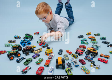 Happy little boy playing gingembre sur le sol avec de petites autos autour de lui Banque D'Images