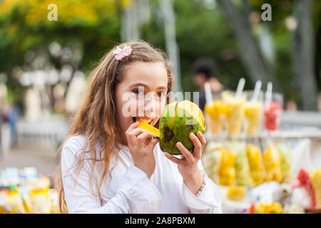 Belle jeune fille à Paseo Bolivar Square dans la ville de Cali en Colombie de manger les fruits tropicaux Banque D'Images