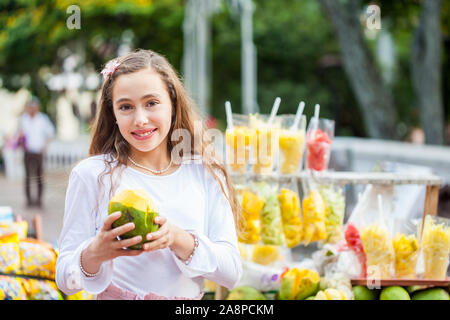 Belle jeune fille à Paseo Bolivar Square dans la ville de Cali en Colombie de manger les fruits tropicaux Banque D'Images