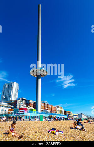 Des gens assis sur la plage avec le 162m de haut de la tour d'observation i360 de British Airways sur le front de mer, Brighton, UK Banque D'Images