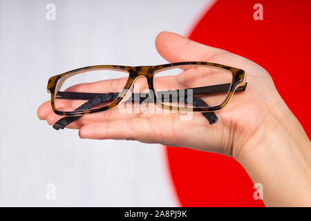 Close up of hand holding une paire de lunettes avec un drapeau du Japon Banque D'Images