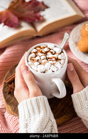 Female hands holding tasse de chocolat chaud avec des guimauves et sauce au chocolat. Automne chaleureux confort alimentaire Banque D'Images