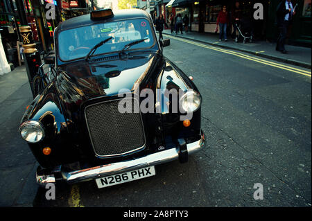 Londres, Royaume-Uni - 14 octobre 2011 : un taxi brillant, connu traditionnellement sous le nom de taxi noir, est stationné dans la rue sombre du centre de Londres. Banque D'Images