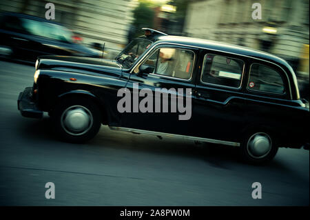 La cabine noire se déplace dans un flou de mouvement sur une rue londonienne Banque D'Images