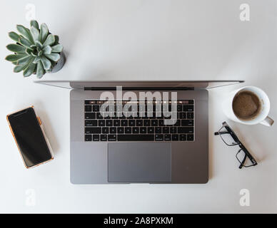 Vue supérieure de l'espace de travail avec ordinateur portable, téléphone, verres et café. Banque D'Images