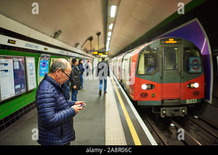 Un représentant de l'Asie personnes âgées en attente d'un train de tube sur le métro de Londres. Banque D'Images