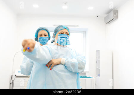 Une infirmière robes une chirurgien dans un costume stérile avant la chirurgie. Banque D'Images
