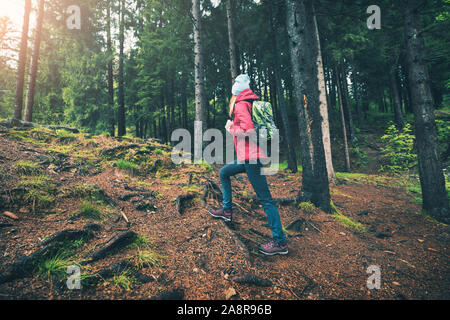 Jeune femme avec un sac à dos vert forêt au coucher du soleil au printemps Banque D'Images